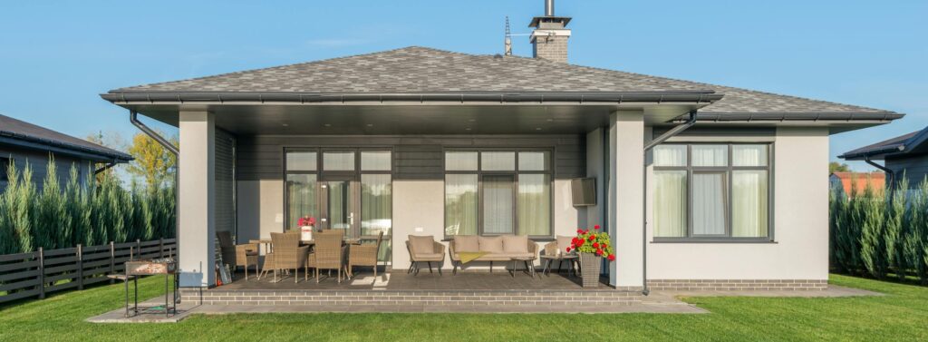 Contemporary house exterior with a large backyard patio and manicured lawn.