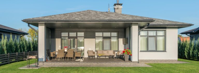 Contemporary house exterior with a large backyard patio and manicured lawn.