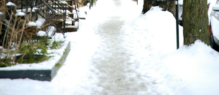 Snowy sidewalk and residential architecture capture Montreal's winter charm.
